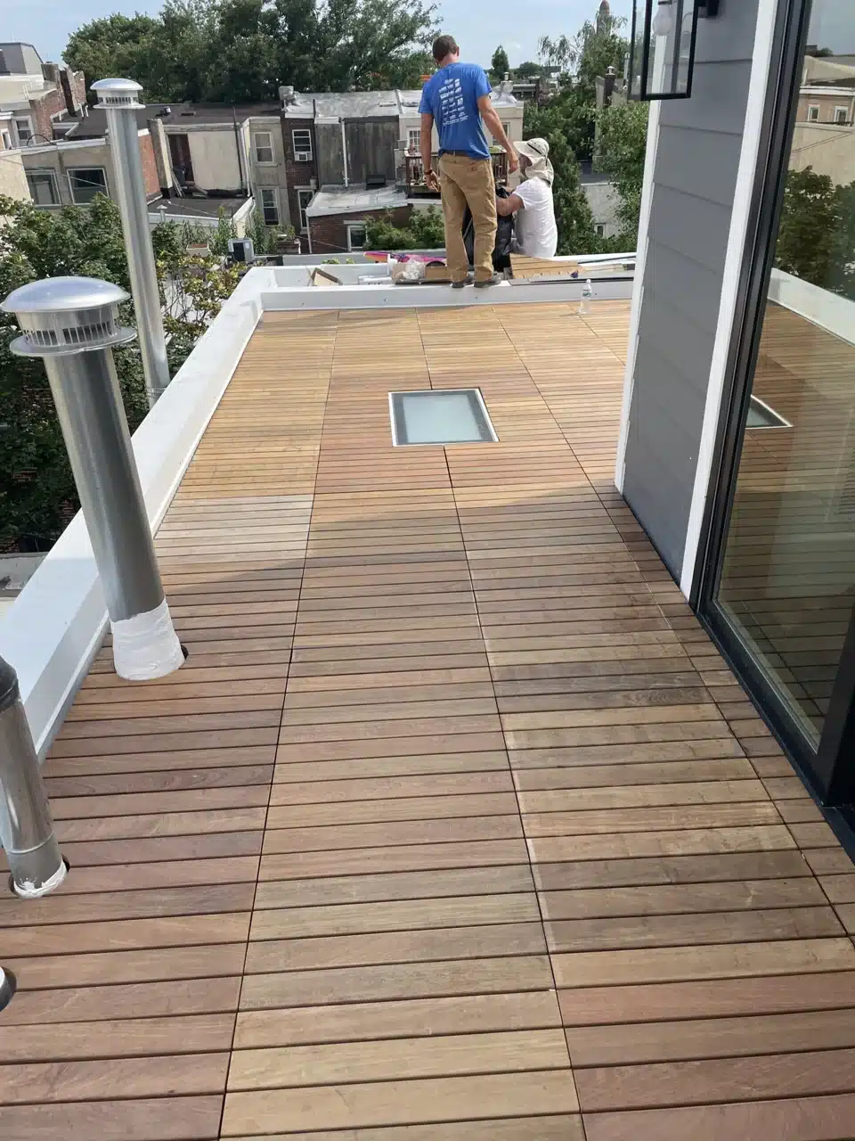 Roofing professionals at work on a rooftop deck with a walkable skylight
